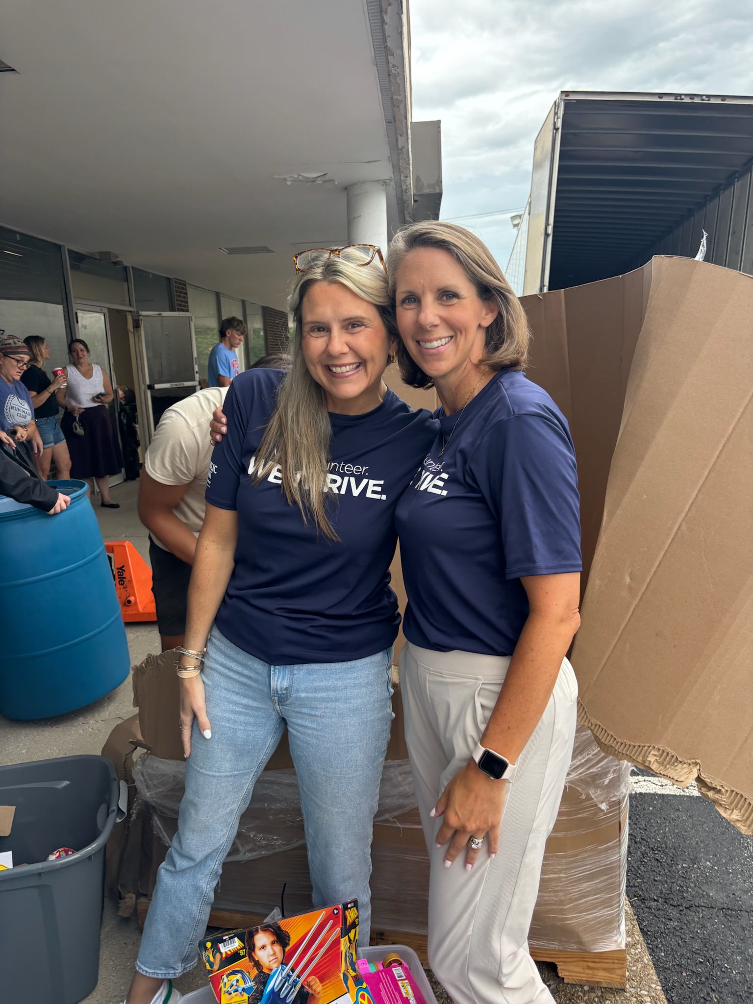 Two volunteers smiling among the toy donations