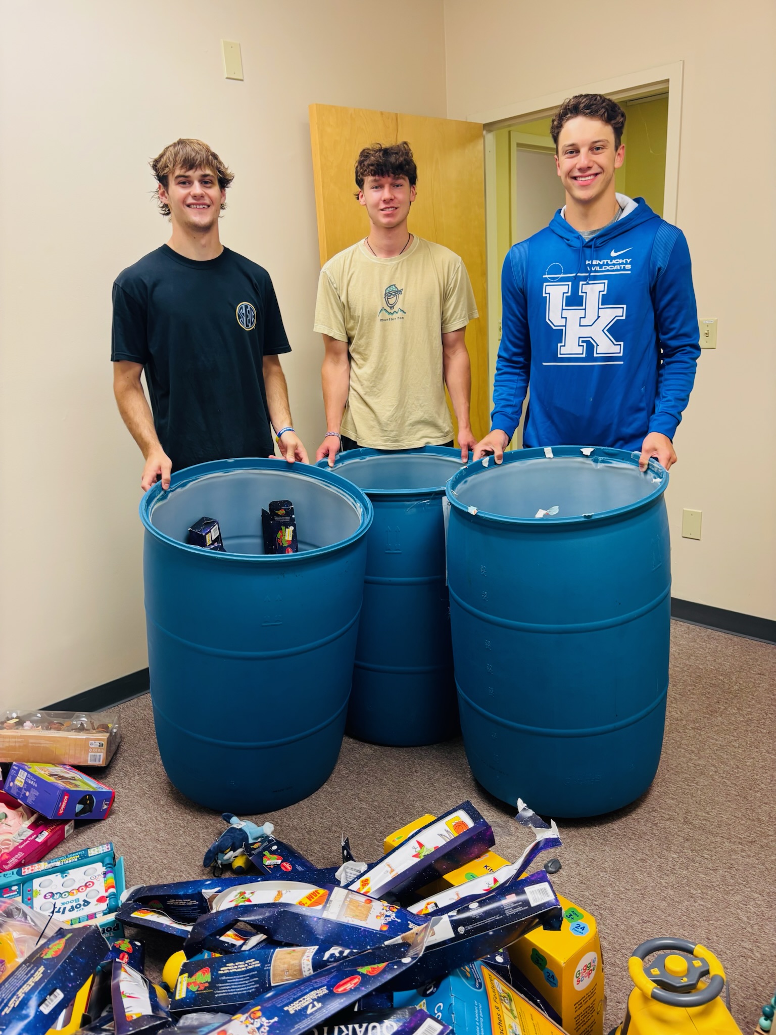 Three volunteers with blue sorting bins full of toys
