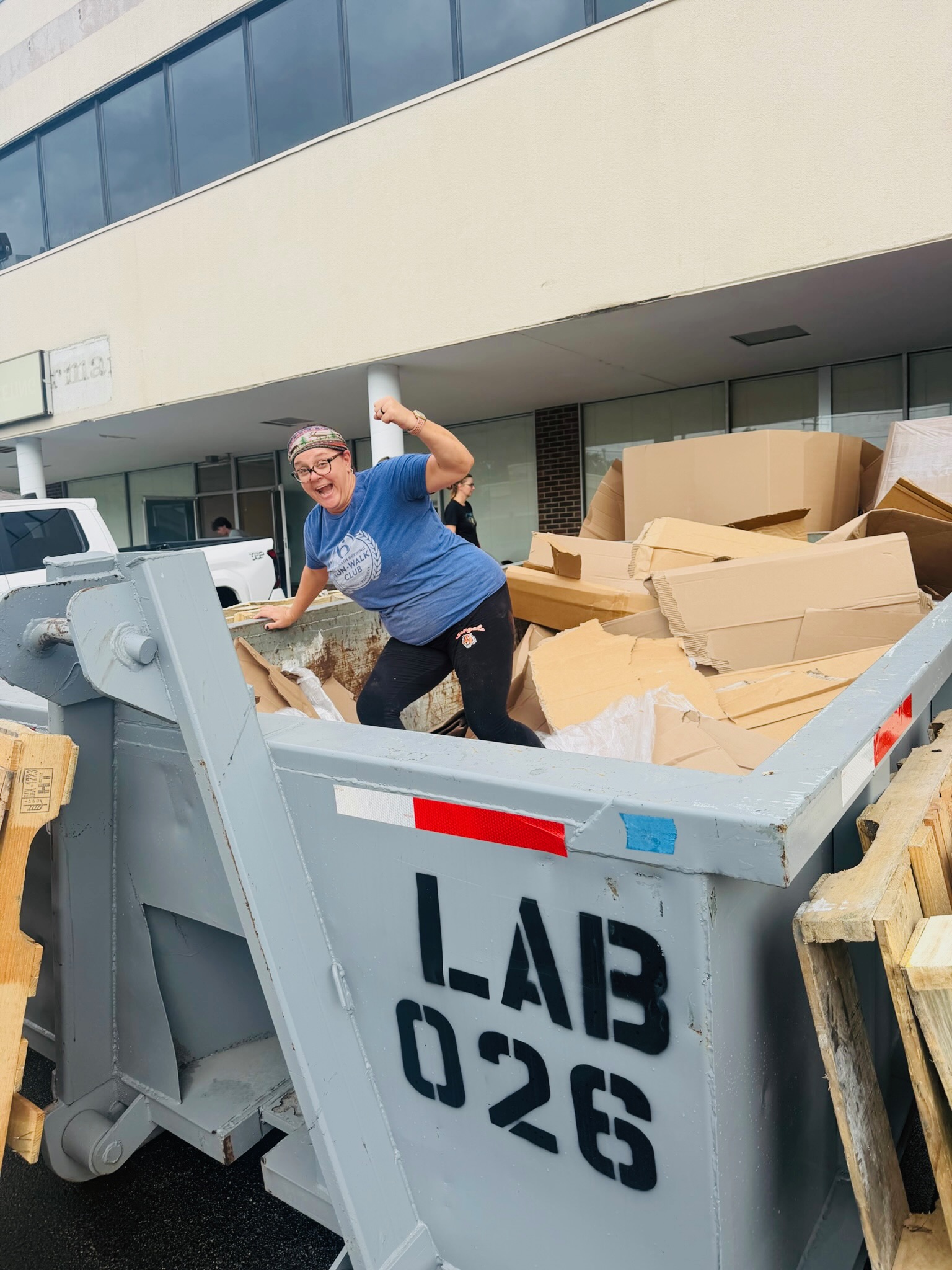 Volunteer breaking down boxes in the cardboard dumpster