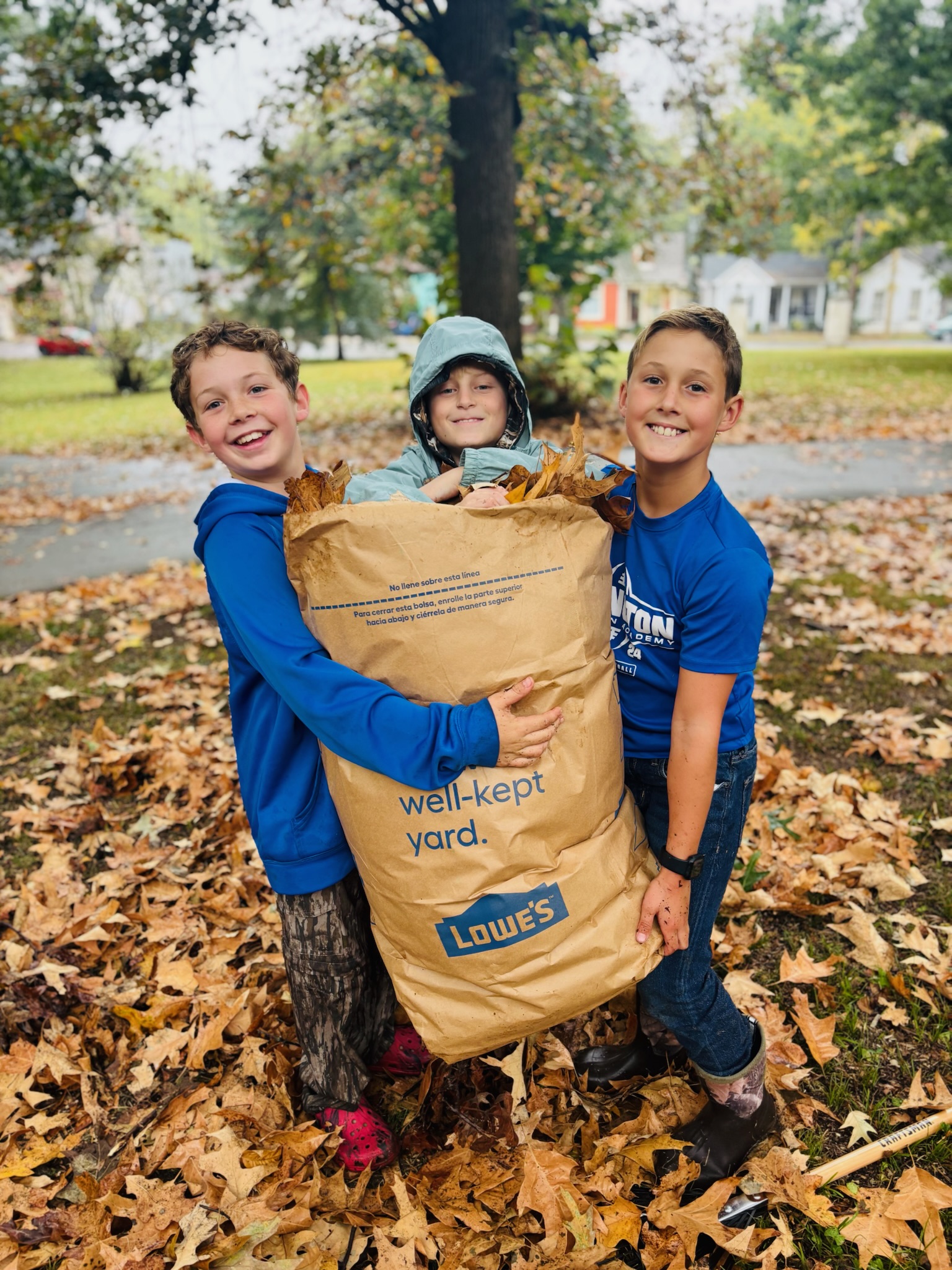 Kids holding up a full leaf bag at The Nest