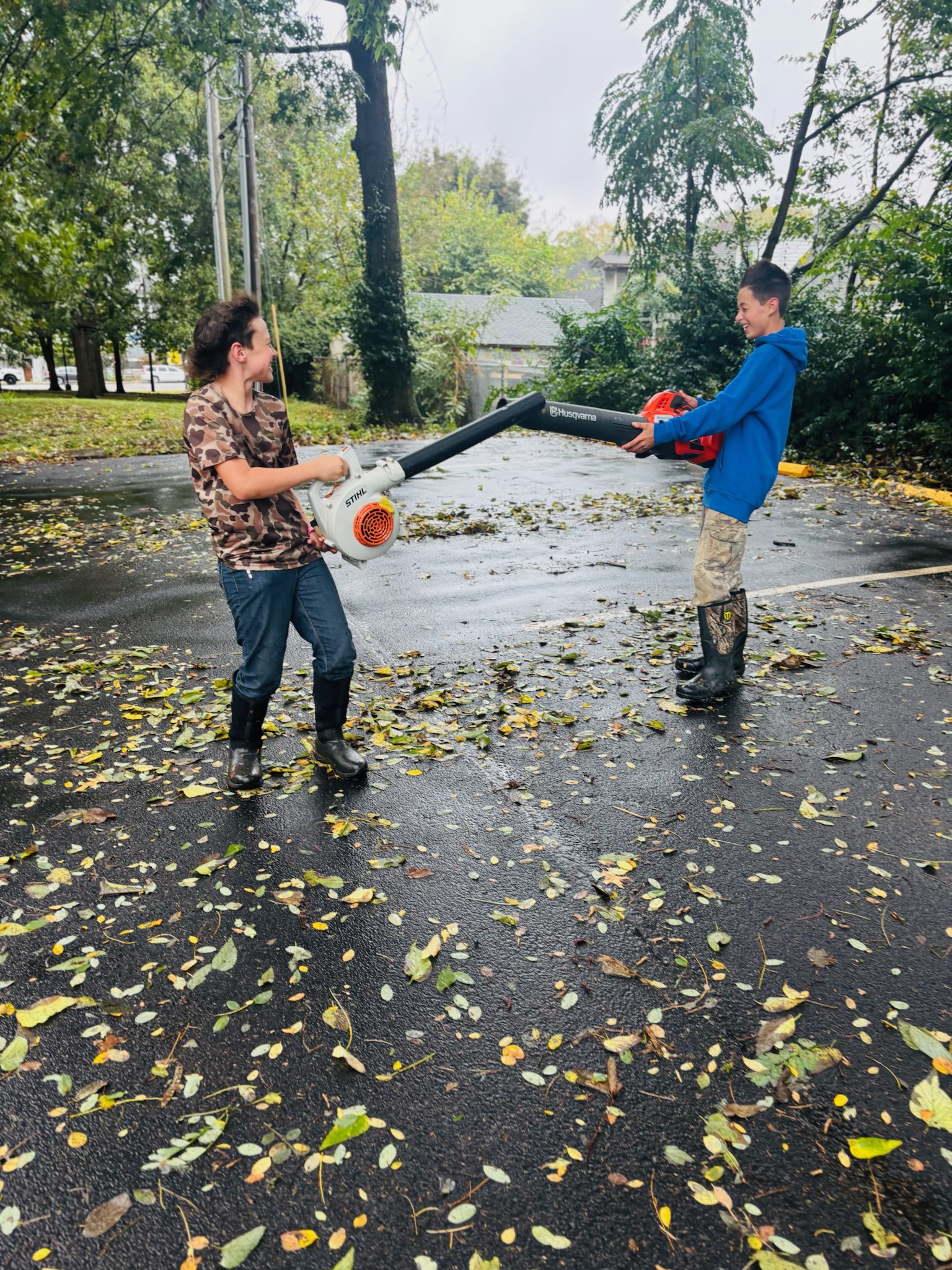 Volunteers clearing leaves off the driveway with a leaf blower