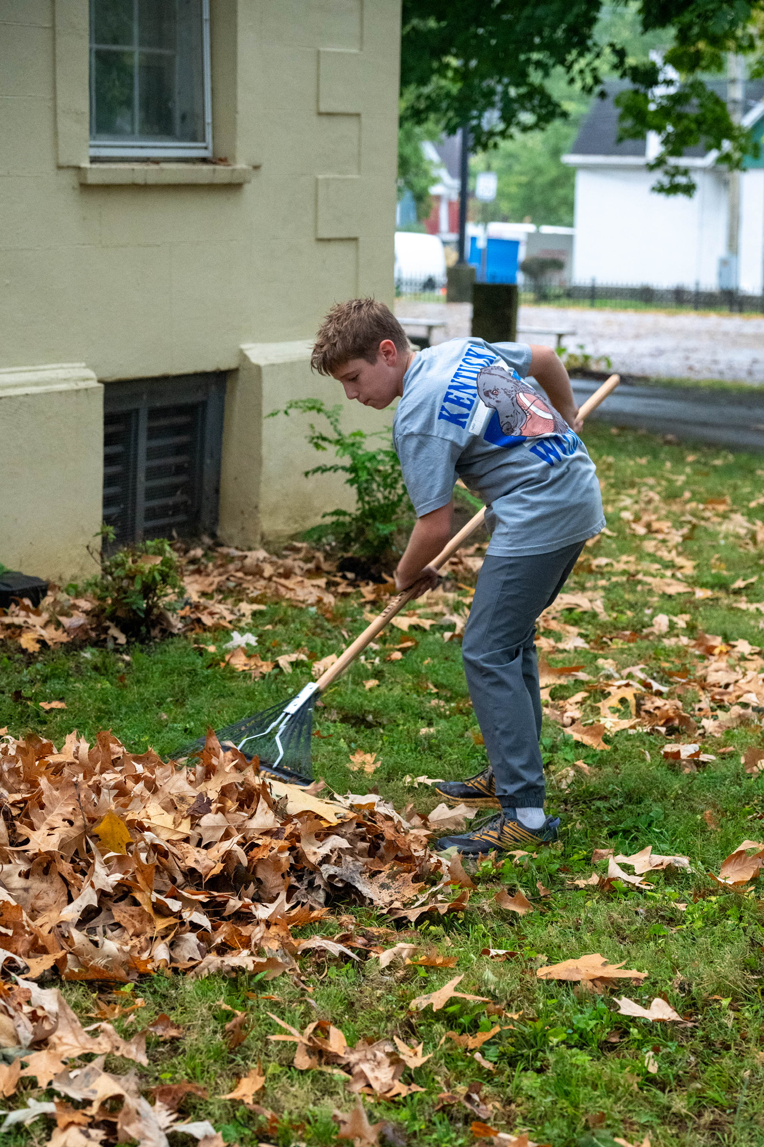 Young volunteer raking leaves beside The Nest